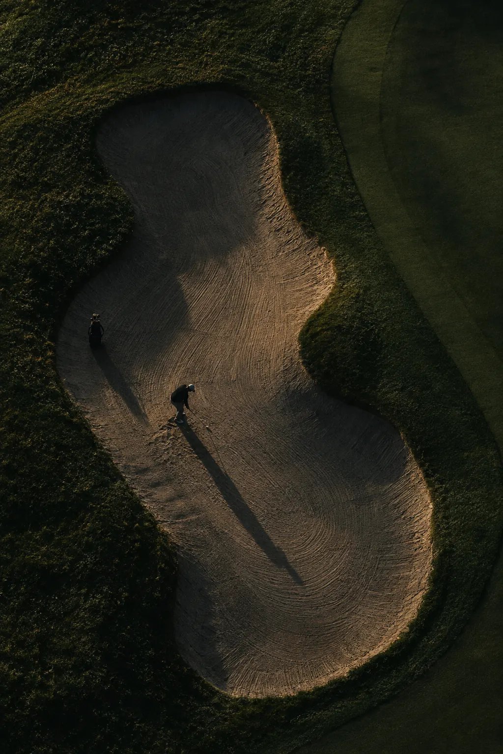 An aerial view of a sculpted bunker beside a fairway.